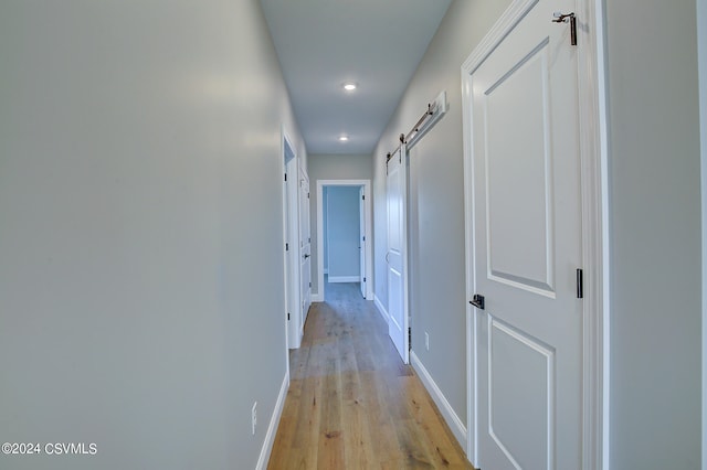 hallway featuring a barn door and light wood-type flooring