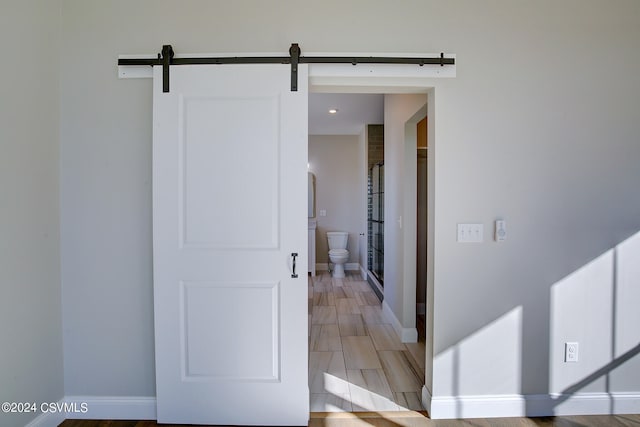 corridor with light hardwood / wood-style flooring and a barn door