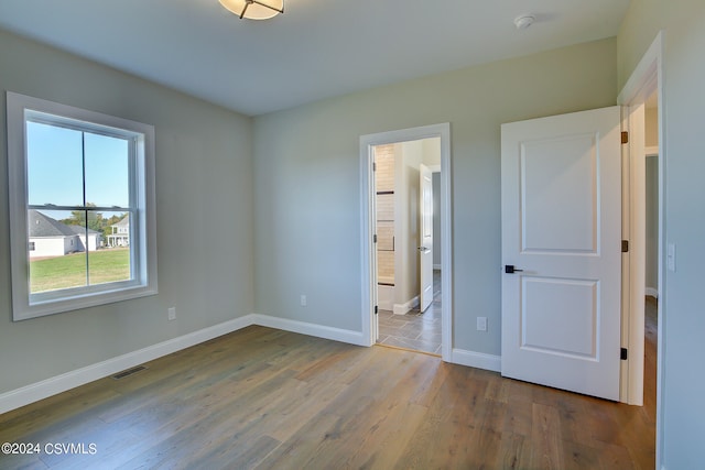 unfurnished bedroom with wood-type flooring and ensuite bath