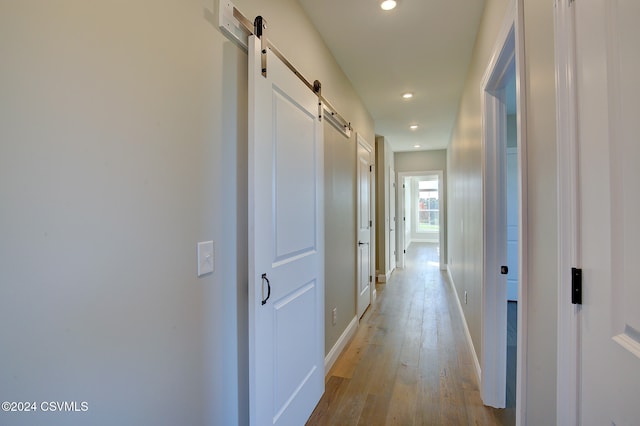 hall featuring a barn door and light hardwood / wood-style flooring