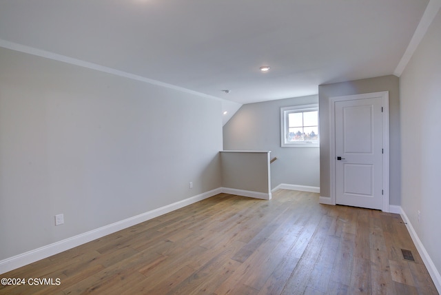 additional living space with vaulted ceiling and light hardwood / wood-style flooring