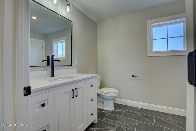 bathroom with vanity, toilet, and a healthy amount of sunlight