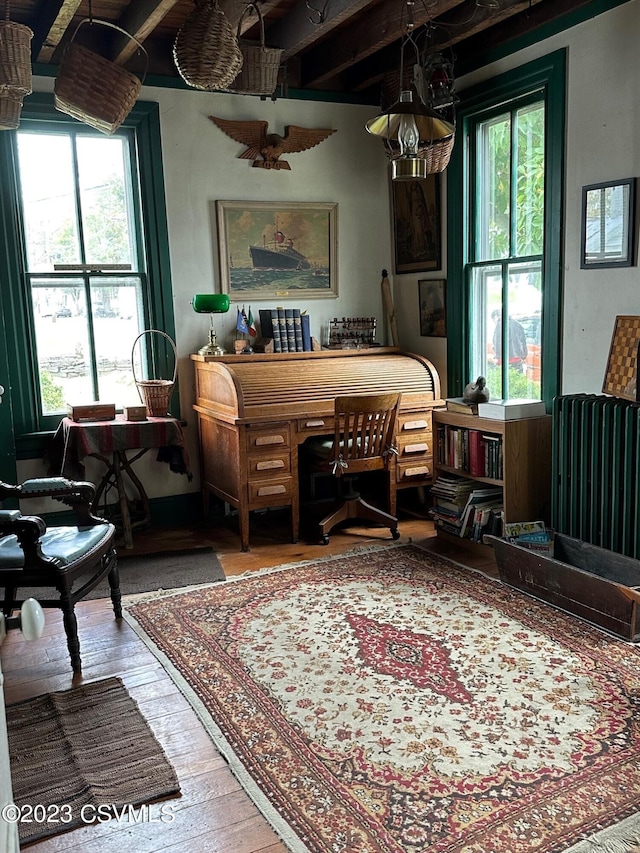 living area with radiator, beamed ceiling, and light hardwood / wood-style floors