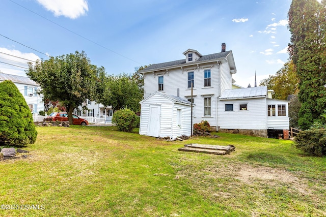 rear view of house featuring a storage unit and a yard