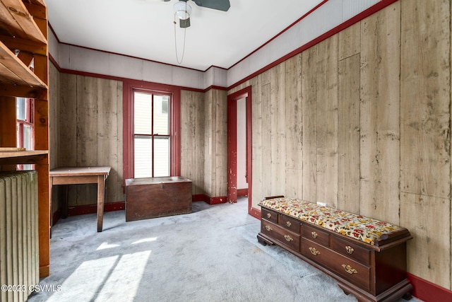 miscellaneous room with light carpet, wooden walls, ceiling fan, and radiator