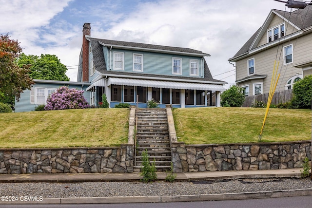 view of property featuring a front lawn and a sunroom