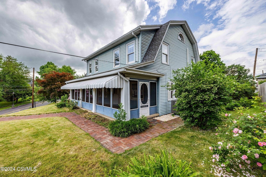 view of property exterior with a lawn and a sunroom