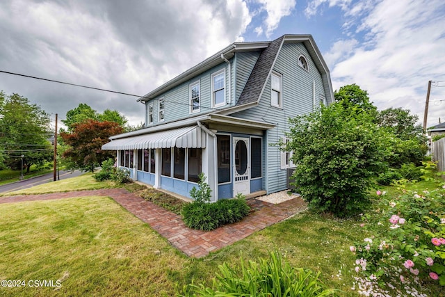 view of property exterior with a lawn and a sunroom