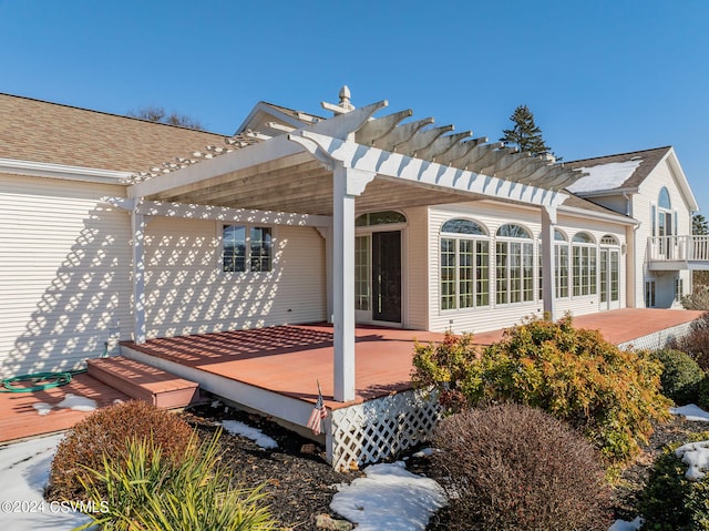 back of property featuring a wooden deck and a pergola