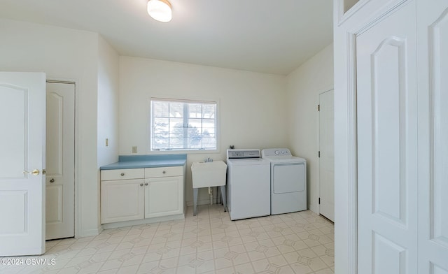 clothes washing area with cabinets, washing machine and dryer, and sink