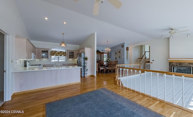 kitchen featuring lofted ceiling, light wood-type flooring, ceiling fan with notable chandelier, and kitchen peninsula