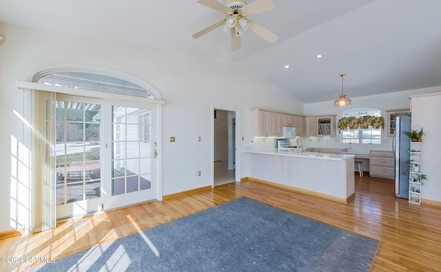 kitchen with stainless steel refrigerator, ceiling fan, decorative light fixtures, kitchen peninsula, and light wood-type flooring