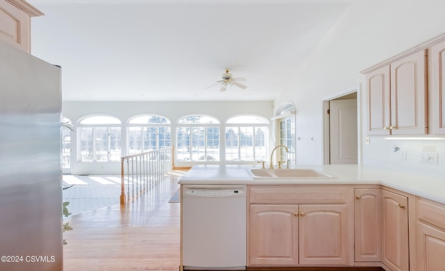 kitchen featuring stainless steel refrigerator, white dishwasher, sink, and light brown cabinets