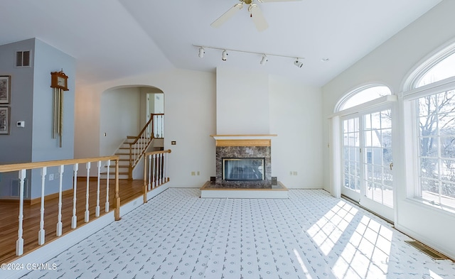 unfurnished living room with ceiling fan, a high end fireplace, and track lighting