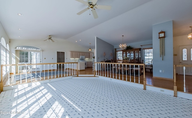 living room featuring hardwood / wood-style flooring, ceiling fan with notable chandelier, and vaulted ceiling