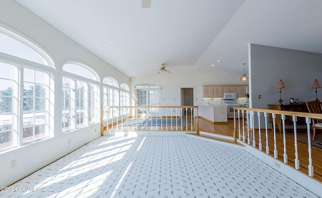 unfurnished sunroom featuring ceiling fan, vaulted ceiling, and a healthy amount of sunlight