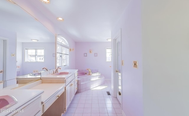 bathroom with tiled tub, vanity, a wealth of natural light, and tile patterned floors