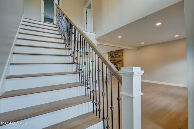 staircase featuring brick wall and hardwood / wood-style flooring