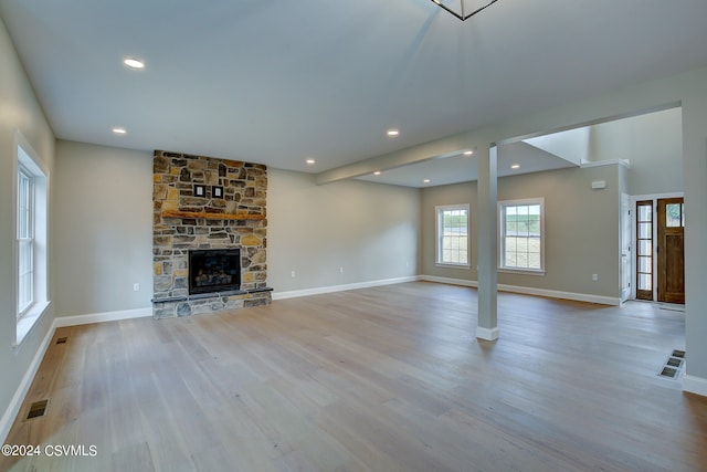 unfurnished living room featuring hardwood / wood-style flooring and a stone fireplace