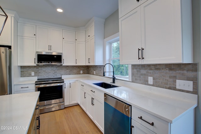 kitchen featuring light hardwood / wood-style flooring, tasteful backsplash, white cabinets, sink, and stainless steel appliances