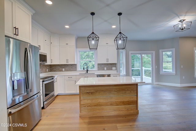 kitchen featuring light hardwood / wood-style flooring, backsplash, white cabinetry, a wealth of natural light, and stainless steel appliances