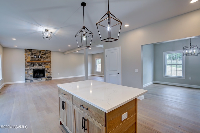 kitchen featuring a wealth of natural light, a center island, light wood-type flooring, and a fireplace