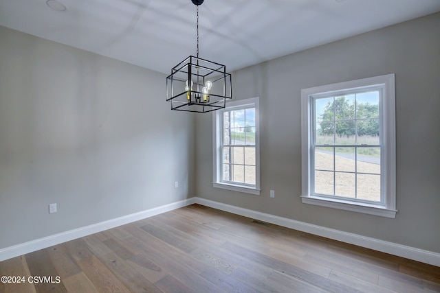 unfurnished dining area featuring hardwood / wood-style floors, a notable chandelier, and a healthy amount of sunlight