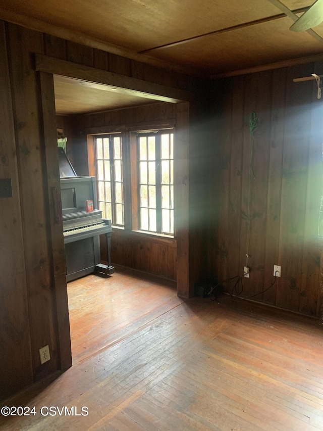 empty room with wood walls, light hardwood / wood-style floors, and ceiling fan