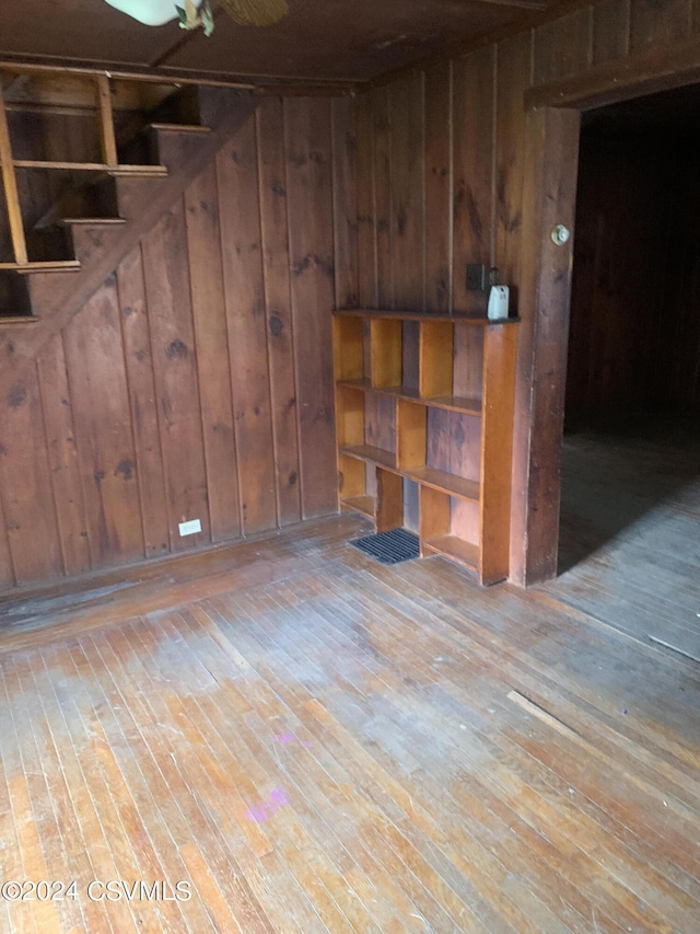 spare room featuring ceiling fan, wood walls, and light hardwood / wood-style flooring