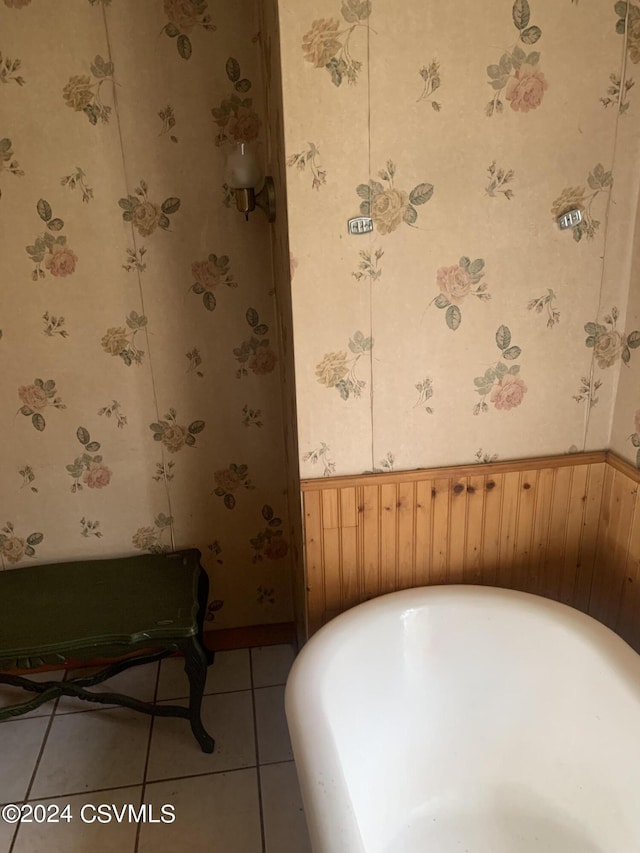 bathroom featuring a bath, wooden walls, and tile flooring