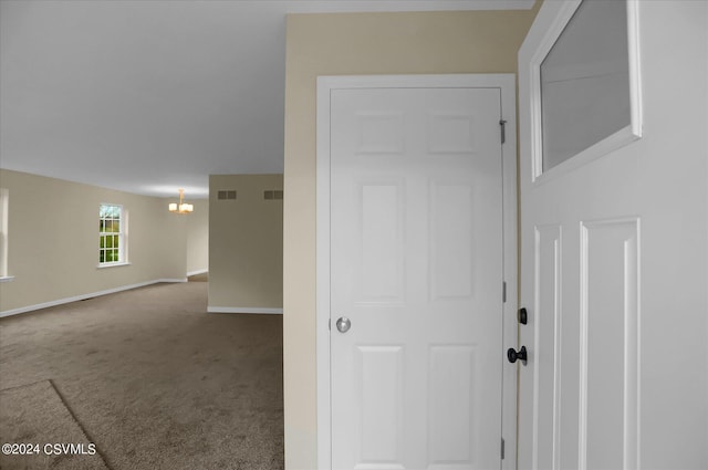 corridor featuring a chandelier and carpet floors