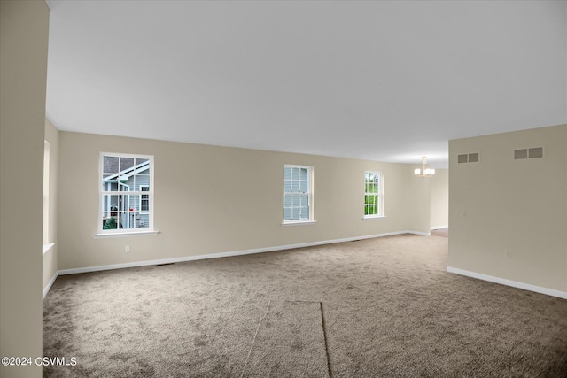 carpeted spare room featuring an inviting chandelier