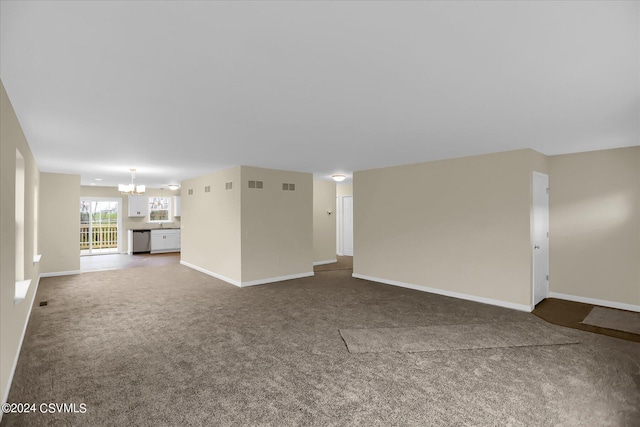 unfurnished living room featuring an inviting chandelier and dark carpet