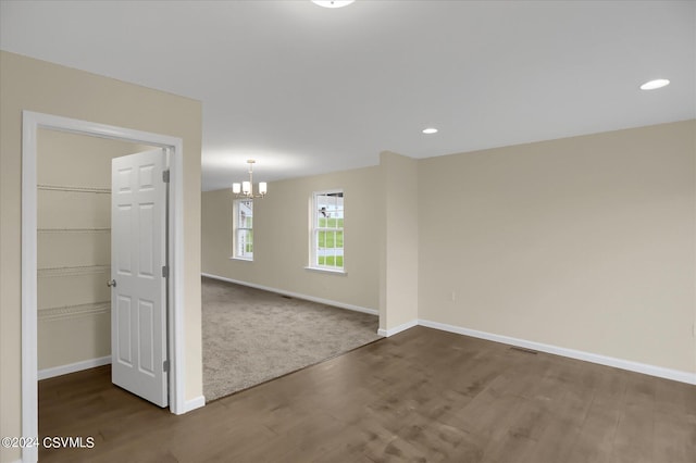 carpeted empty room featuring an inviting chandelier