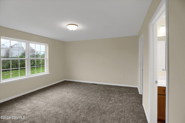 spare room featuring dark carpet