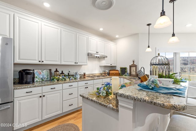 kitchen featuring appliances with stainless steel finishes, white cabinetry, light stone countertops, and light hardwood / wood-style flooring