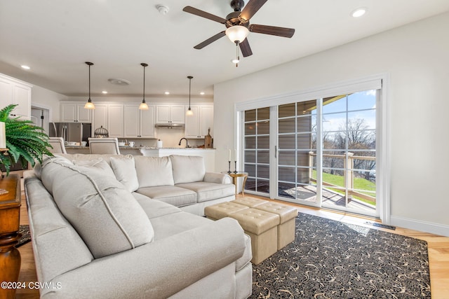 living room with ceiling fan, sink, and light hardwood / wood-style floors