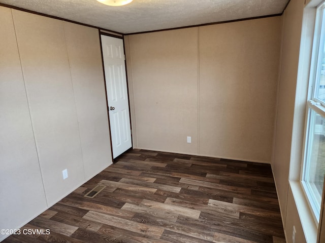 empty room with a textured ceiling and dark wood-type flooring