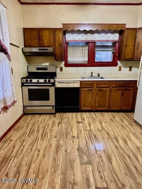 kitchen with under cabinet range hood, a sink, stainless steel range with gas cooktop, light countertops, and dishwasher