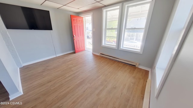 spare room featuring a baseboard heating unit, wood-type flooring, and a paneled ceiling