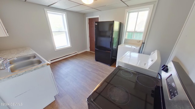 kitchen with a drop ceiling, a baseboard heating unit, black fridge, and hardwood / wood-style floors