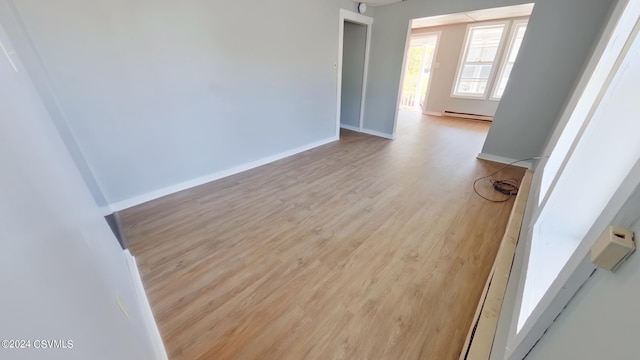 unfurnished room with wood-type flooring and baseboard heating