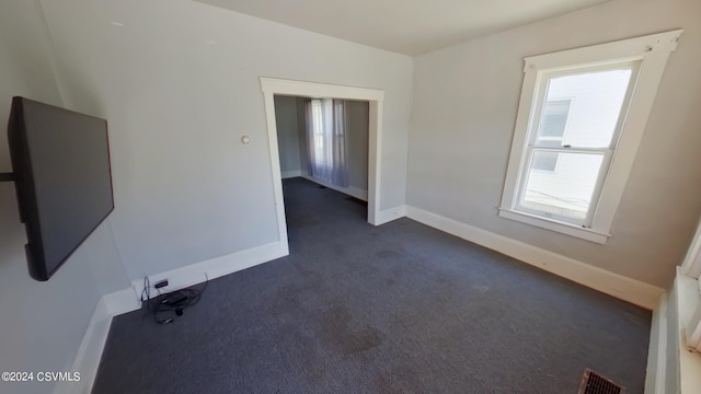 unfurnished room featuring dark colored carpet