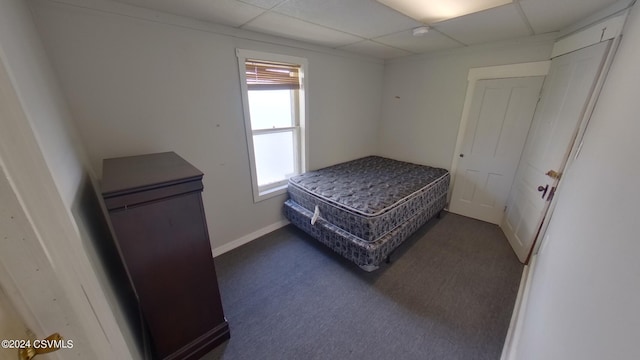 carpeted bedroom with a drop ceiling and multiple windows