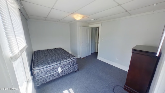 unfurnished bedroom featuring a paneled ceiling, dark carpet, and multiple windows