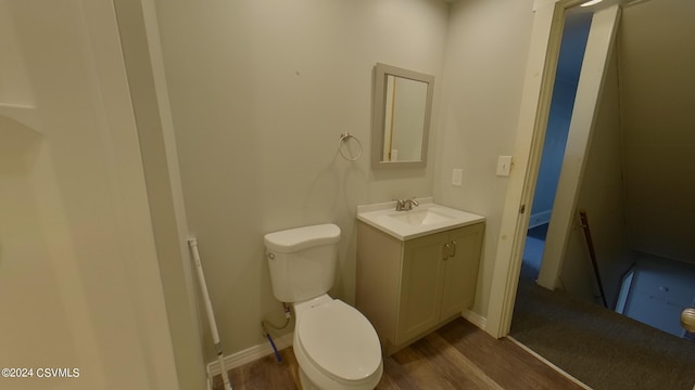 bathroom with hardwood / wood-style flooring, toilet, and vanity