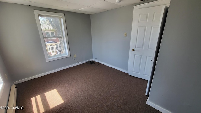 carpeted spare room with a drop ceiling and baseboard heating