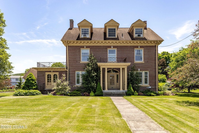 view of front facade with a front yard and a balcony