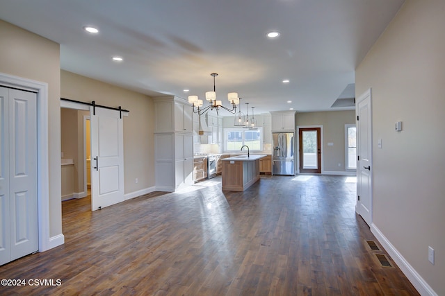 kitchen featuring appliances with stainless steel finishes, a barn door, dark wood-type flooring, pendant lighting, and a center island