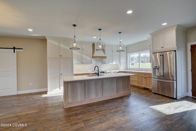 kitchen with dark hardwood / wood-style floors, a barn door, high quality fridge, and a center island with sink